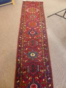 A hand made Iranian Karadja hall runner having geometric design decorated with birds in claret,