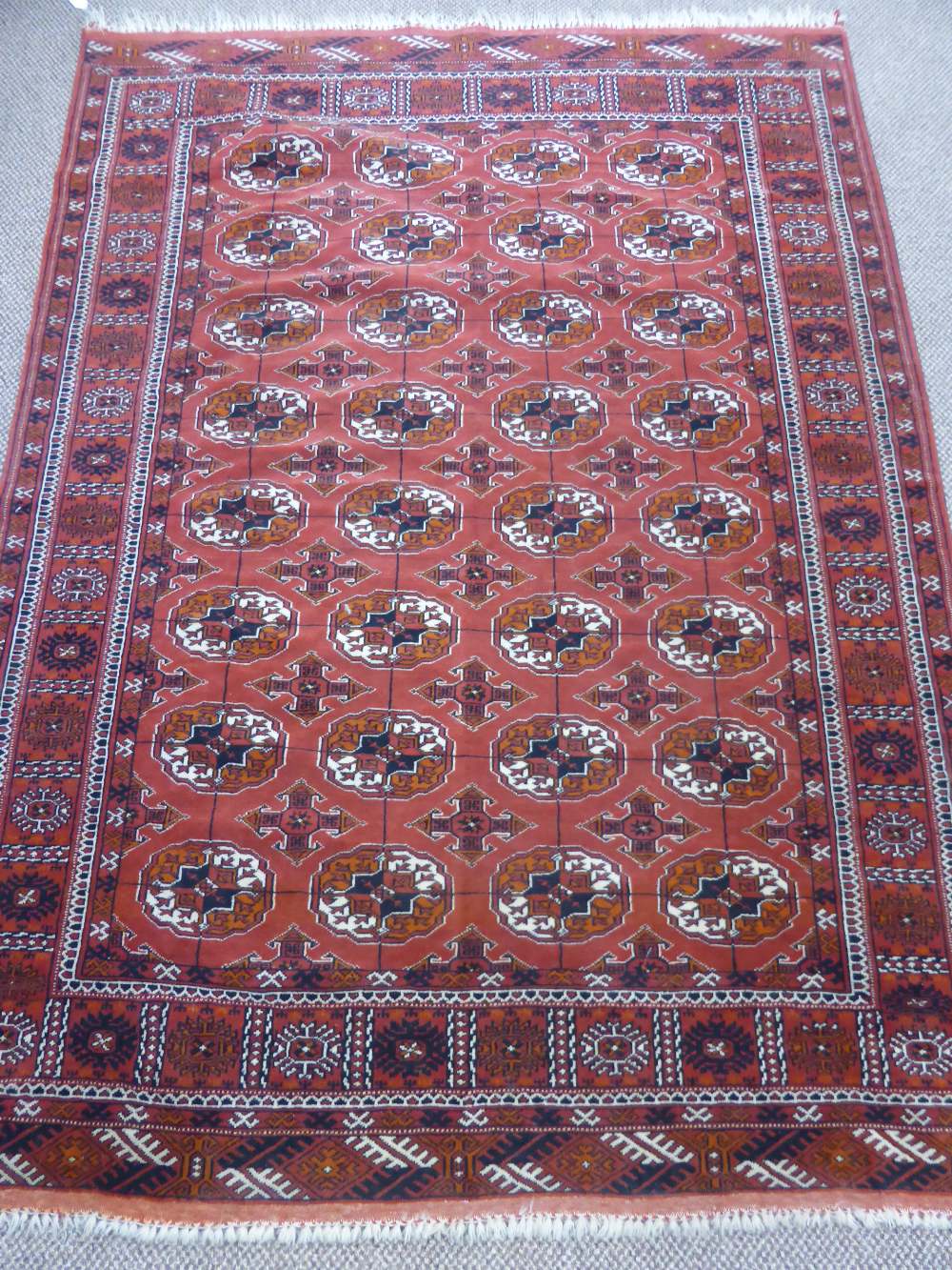 A Vintage Persian Bukhara Rug, cream and terracotta highlights on a soft ruby ground, geometric