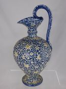 Antique pottery ewer with white flowers on a blue ground, possibly Persian, monogrammed H to base,