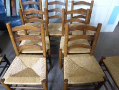 Set of seven oak ladder back dining chairs being rush seated on turned legs and stretchers together