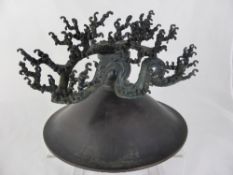 An Oriental Bronze Pillar Candle Stick with raised decoration in the form of ocean waves.