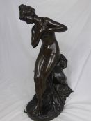 A circa 1900 bronze statue of a naked lady, the figure depicting a feminine nude sitting on a rock,