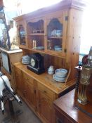 A modern pine dresser, the top having a glazed cabinet to each side with open shelves to centre,