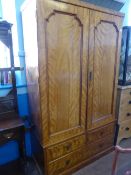 An Edwardian Birch double wardrobe having panelled doors and two sort and one long drawer below,