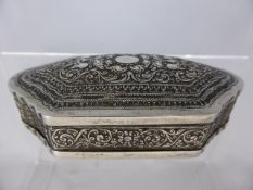 An Indian silver metal trinket box having shaped edges with masks to the top, the base being