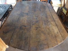 An antique oak planked drop leaf dining table on turned legs, the ends and drop leaves creating an