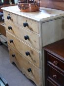 An antique pine chest of drawers having two short and three graduated long drawers with black