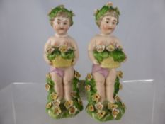 Two hand painted Continental Figures, depicting cherubs with applied primrose and daffodil