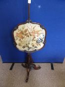 A Victorian mahogany pole screen having floral embroidery in a decorative frame, the screen having