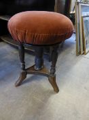 An Edwardian mahogany wind up piano stool on turned supports and tripod feet.