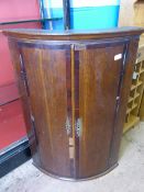 A Georgian Bow Fronted Corner Cupboard with brass key plates, 70 cms x 49 cms.