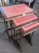 A nest of three mahogany tables having red and gilt leather tops.