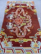 A Mid Twentieth Century Tibetan Wool Rug, the terracotta ground with two dragons chasing a flaming