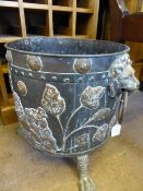 A vintage circular brass and copper log box having ring handles mounted on lion masks, three claw