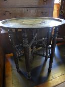 An antique Indian style round brass topped occasional table, the brass top having ornate decoration