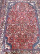 A Middle Eastern wool carpet of foliate design, the carpet of burgundy and blue colouring, approx.