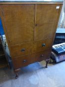 A teak tall-boy by Raleigh Furniture having a cupboard to the top with two shelves to the interior