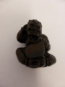 An antique carved Japanese rosewood Netsuke depicting a mythological character clasping a musical