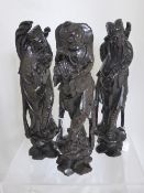 Three oriental wooden decorative carvings depicting wise men, the figures with silver inlay,