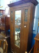 An Oak Arts and Crafts Single Wardrobe with glass fronted door and copper panels depicting sea