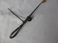 An unusual antique metal utensil having two prongs and a candle holder.