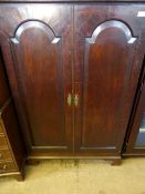 An Edwardian Mahogany Hall Cupboard with two arched panel doors on bracket feet with three shelves