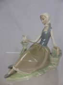 A Lladro Porcelain figure of a seated young woman with duck, 22 cms high.