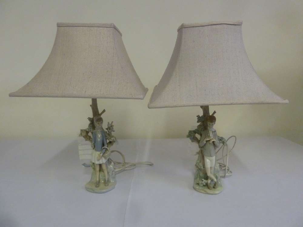 Two Lladro figurines of a boy and a girl leaning against trees, converted to table lamps - A/F