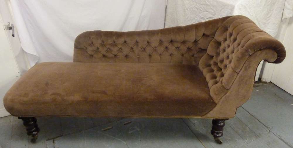 A Victorian chaise longue upholstered button back on four turned cylindrical legs