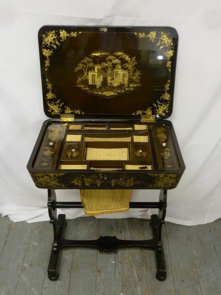 A Victorian ebonised Chinoiserie sewing table hinged cover on scrolling supports