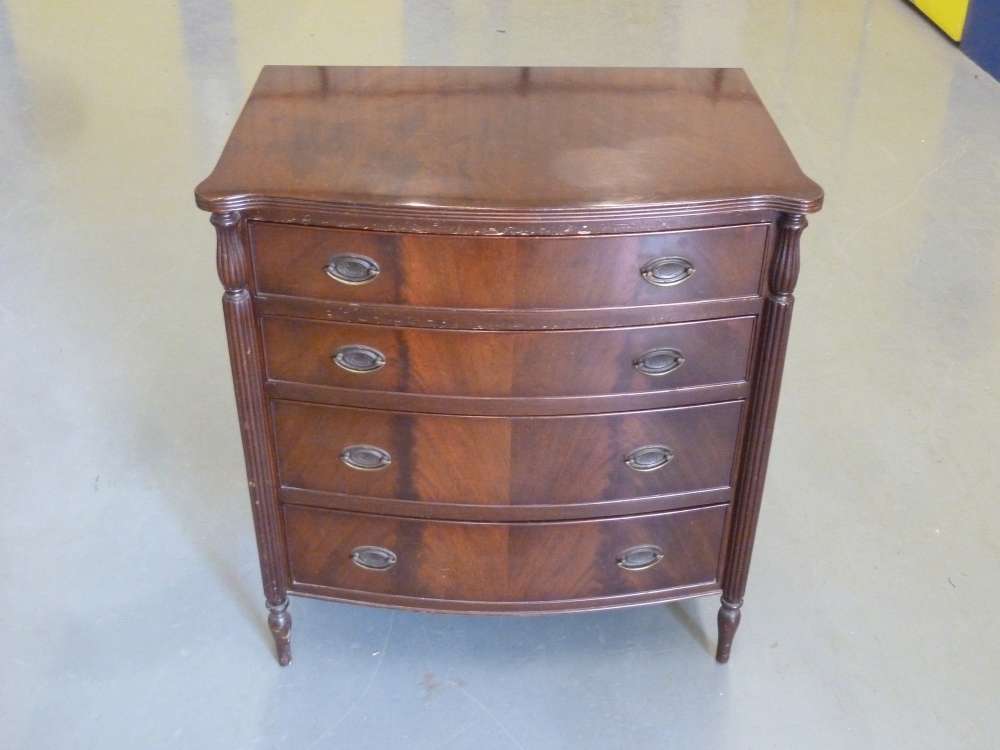 Mahogany bow fronted chest of drawers with brass swing handles on four baluster legs