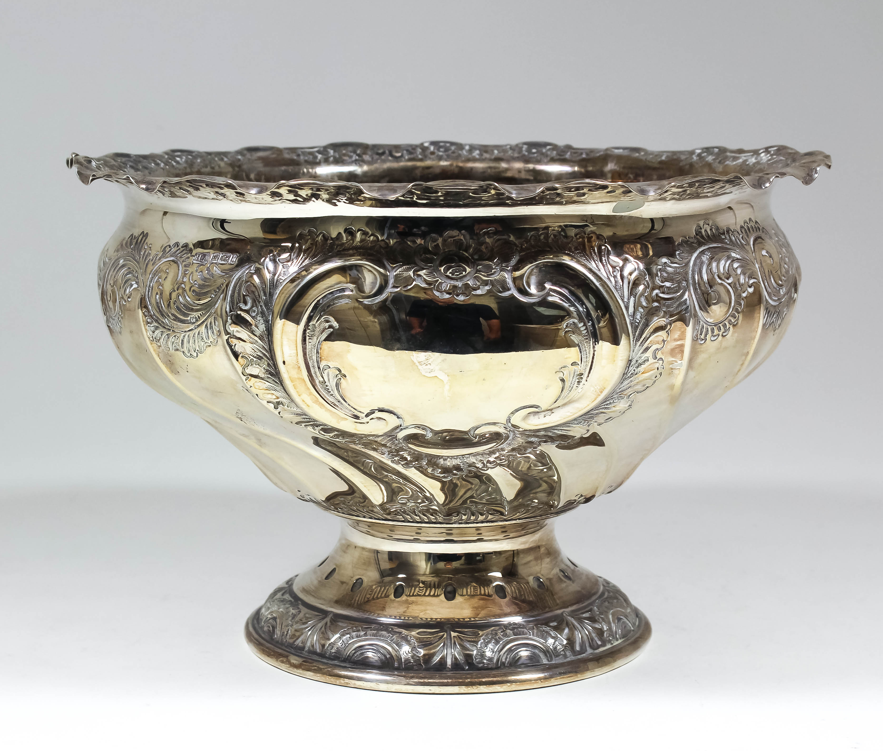 A late Victorian silver circular punch bowl, the shaped rim cast with scroll and floral ornament,