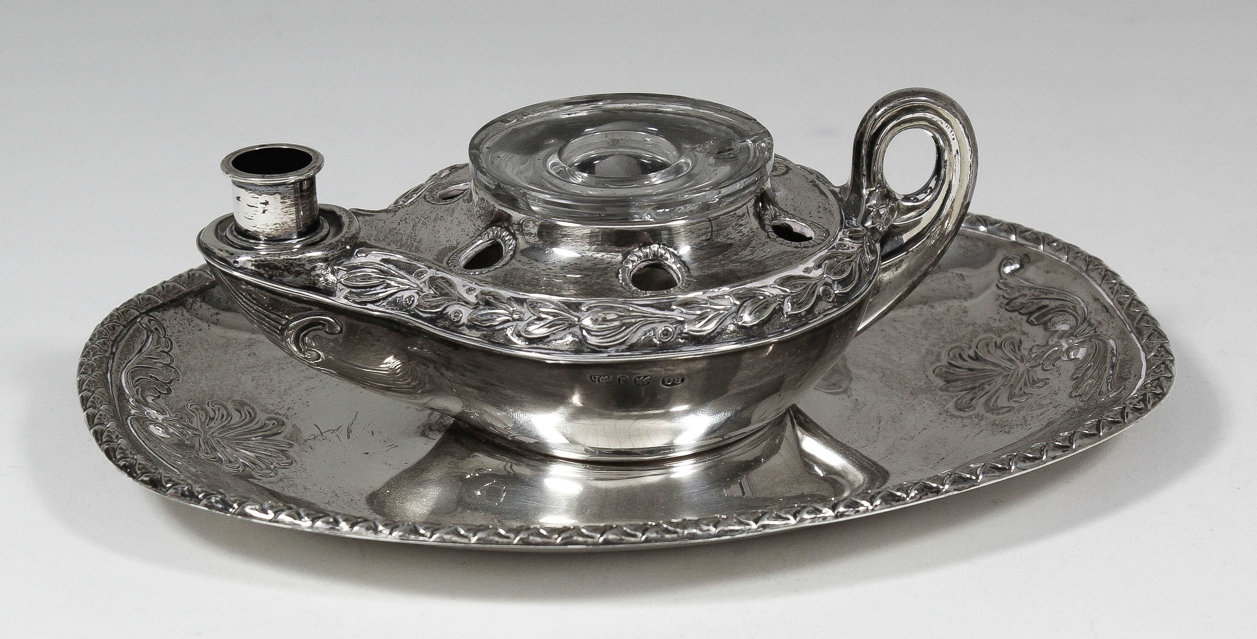 A William IV silver oval inkstand of classical oil lamp pattern, embossed with a band of leafage,