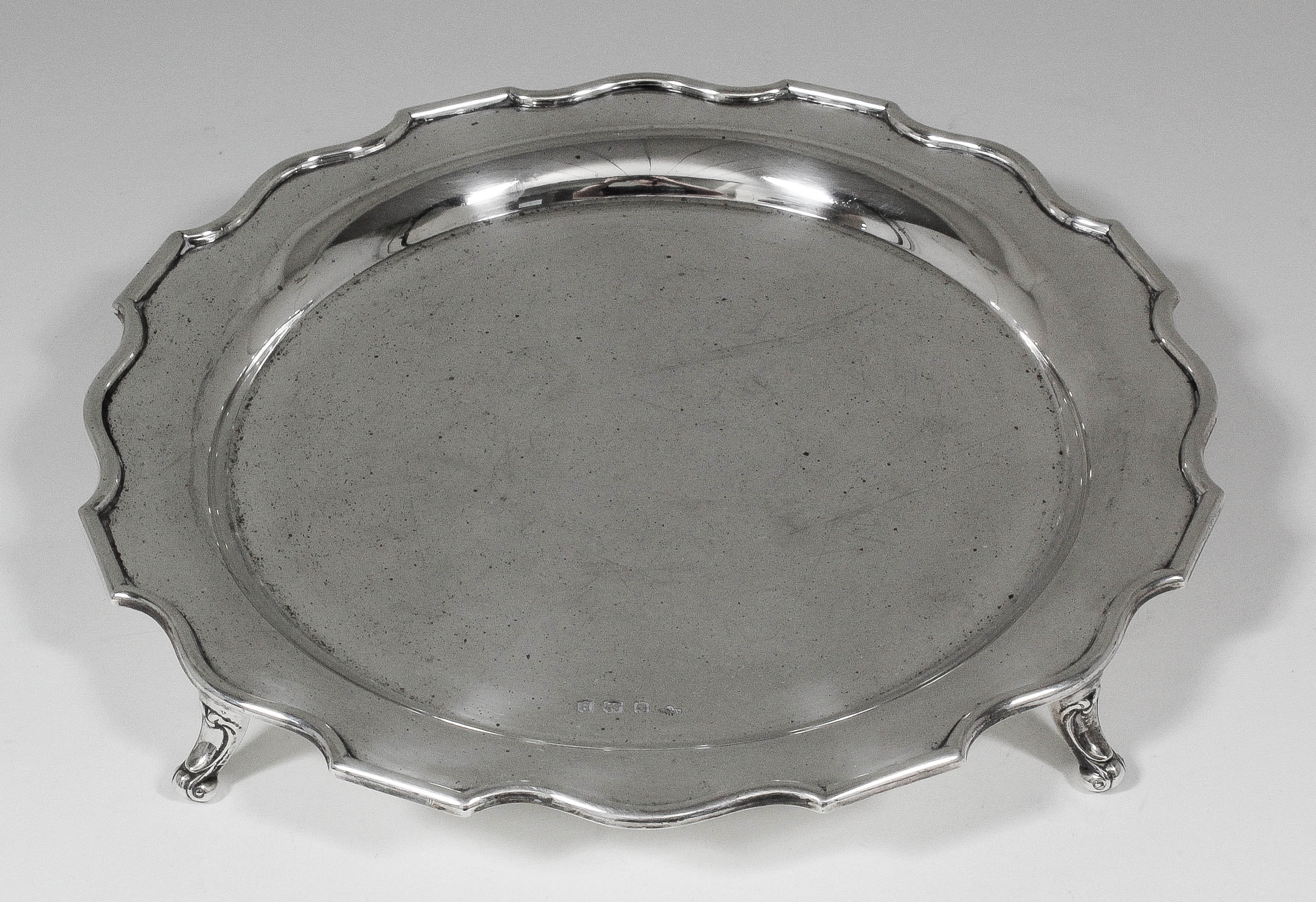 A George VI silver circular salver with shaped rim on three bracket feet with scroll toes, 10.25ins