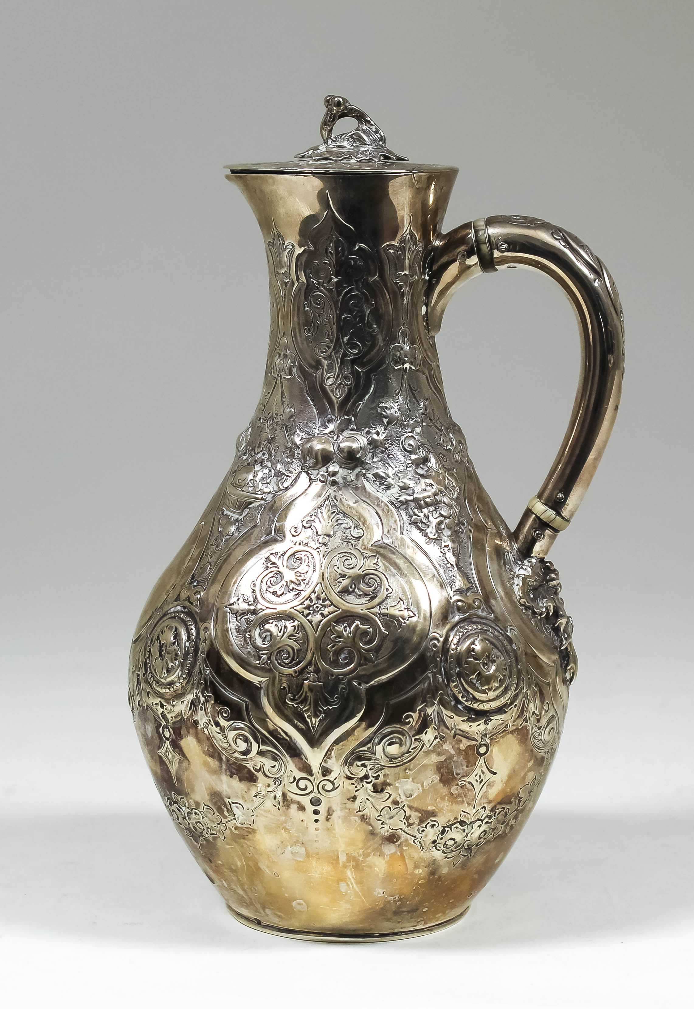 A Victorian silver hot water jug, the whole embossed with shaped cartouche, strap work, baskets of