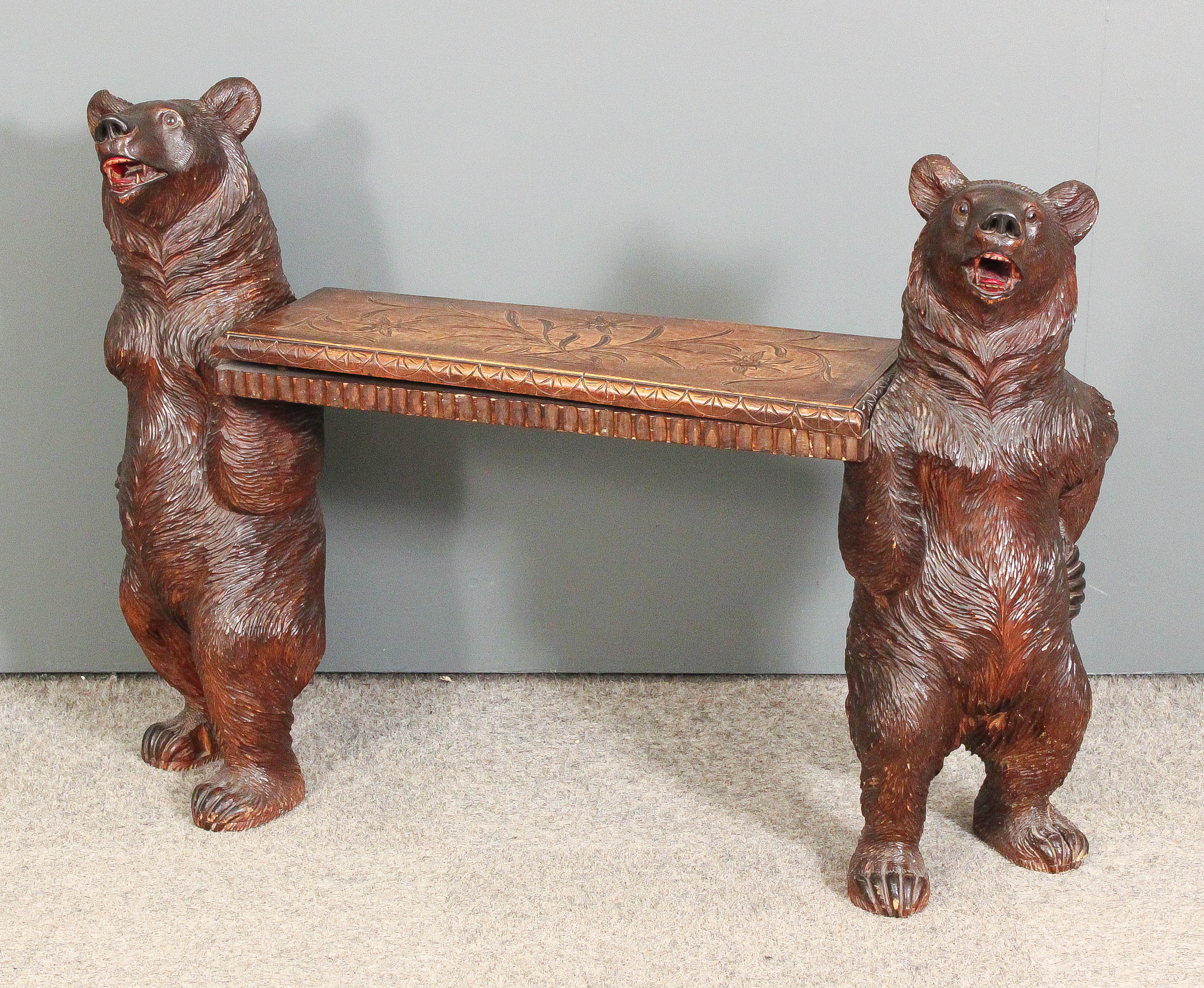 A late 19th Century Swiss carved lindenwood hall bench supported by two carved standing figures of