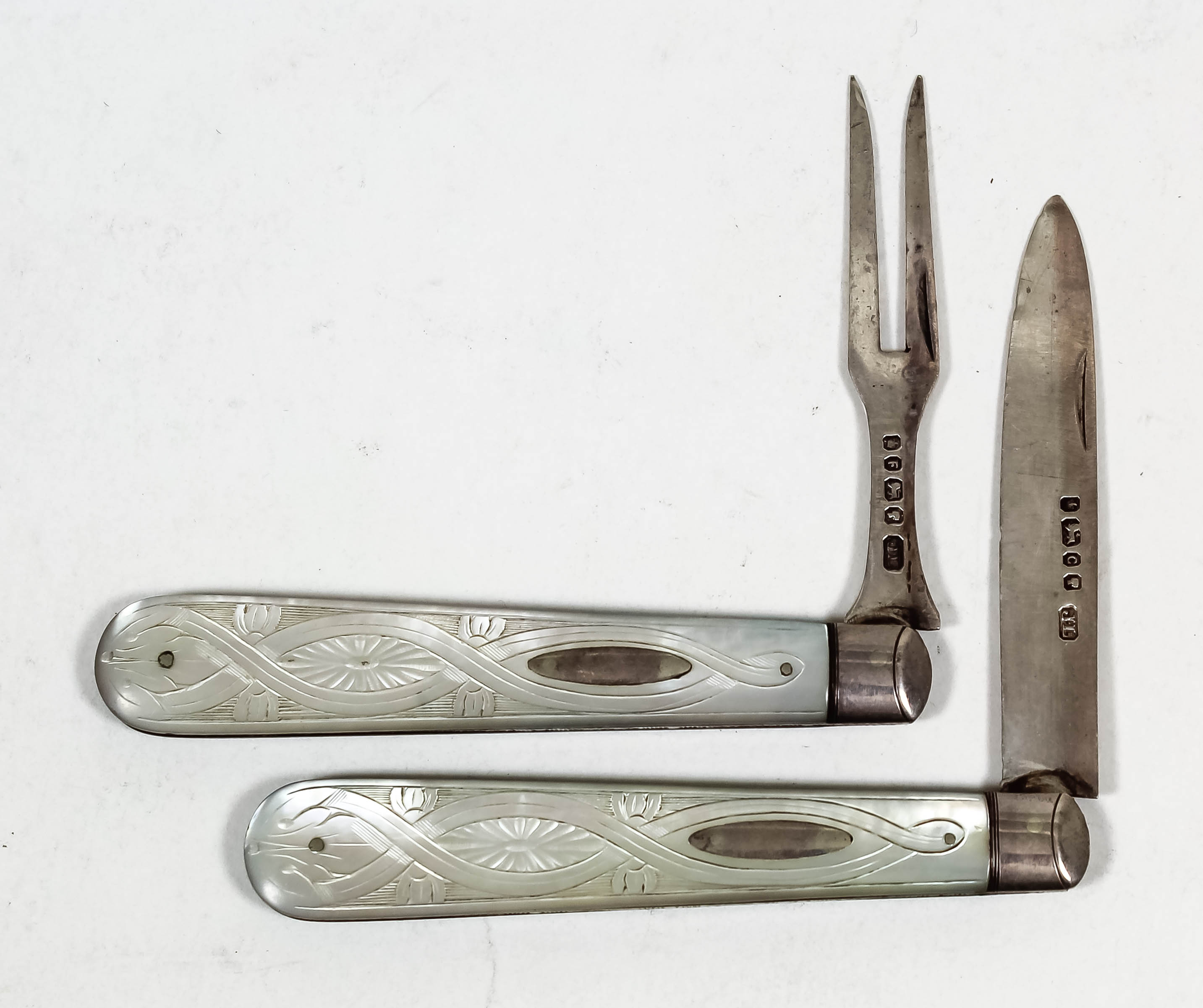 A Victorian silver and mother of pearl handled pocket fruit knife and fork, the handles carved with