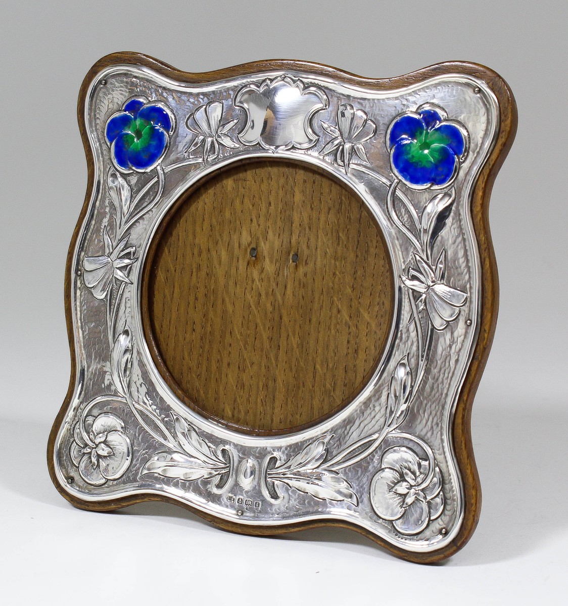 An Edward VII enamelled silver photograph frame of shaped outline and of Art Nouveau design, the