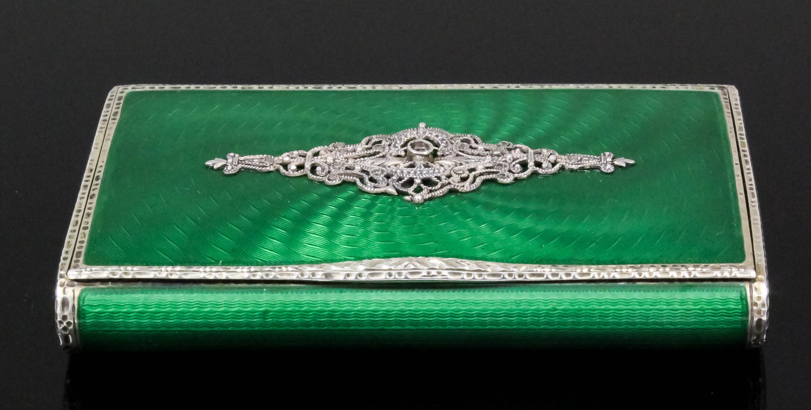 An early 20th Century Continental silver and green enamel rectangular snuff box, the lid with cast