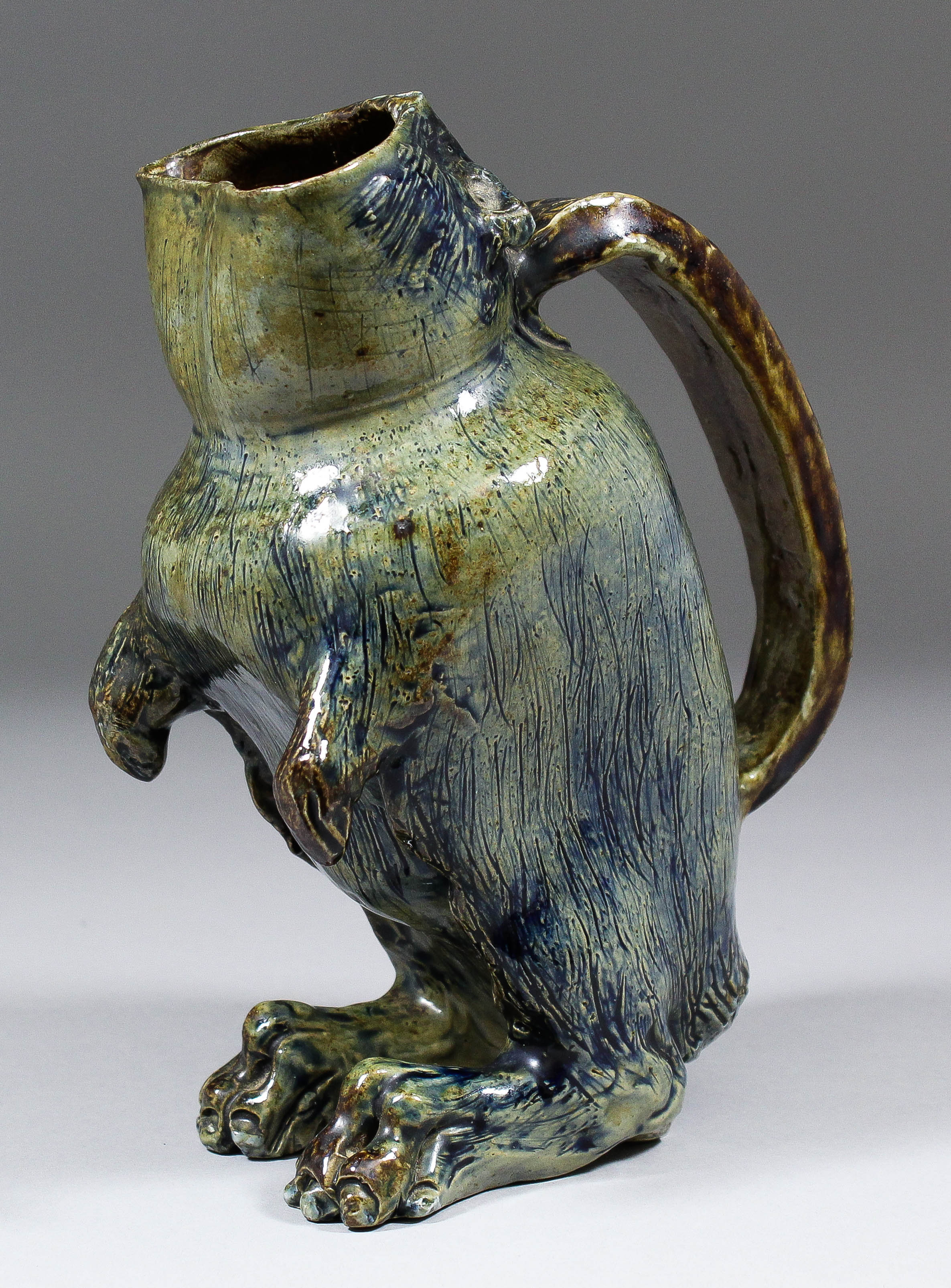 A Martin Bros salt glazed stoneware spoon warmer modelled as a grotesque animal with gaping mouth by