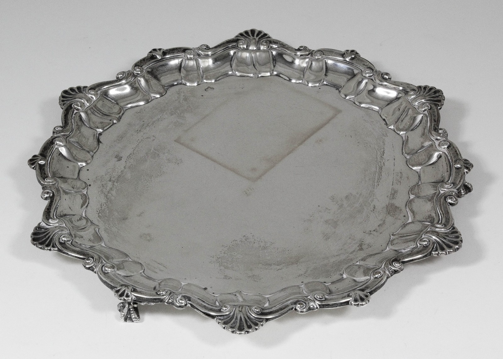 An Edward VII silver circular salver of Georgian design, the shaped rim with cast shell, C and S-