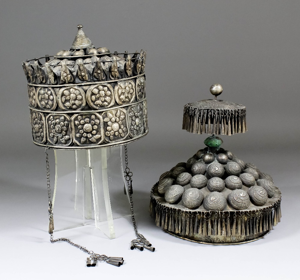 A Chinese Miao silvery metal two tier headdress embossed with shell motifs and hung with tassels,