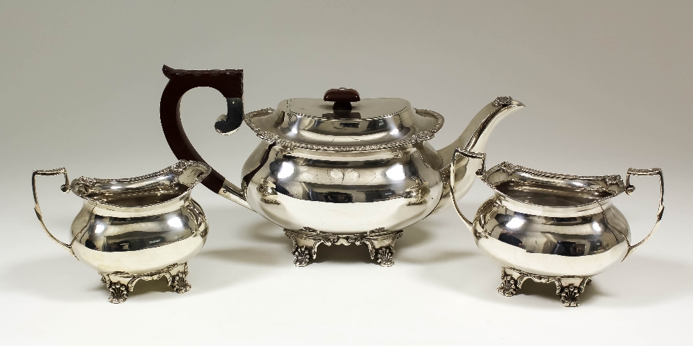 A George V silver rectangular three piece tea service with bead and shell mounts, leaf capped