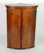 GEORGE III OAK AND MAHOGANY CROSSBANDED BOW FRONTED CORNER CUPBOARD, the moulded cornice above a