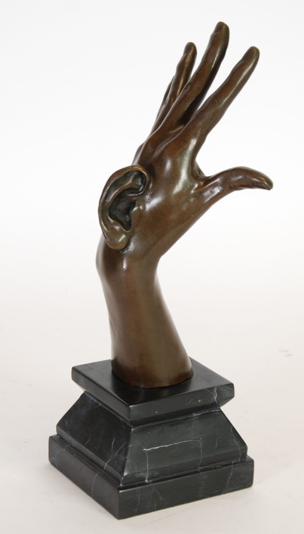 AFTER MILO, PATINATED BRONZE HAND AND EAR SCULPTURE, raised on a veined black slate pedestal base,