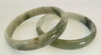 A PAIR OF MOTTLED JADE BANGLES, 1.5cm diameter, ANOTHER PAIR OF GREEN HARD STONE BANGLES, TWO