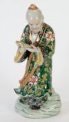 JAPANESE IMARI PORCELAIN FIGURE, modelled as a man standing in floral robe reading from an open