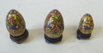 GRADUATED SET OF THREE MODERN CHINESE CLOISONNE EGG SHAPED ORNAMENTS, each decorated in colours, on