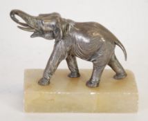 WHITE METAL MODEL OF AN ELEPHANT, well moulded with raised trunk on an oblong onyx base, 4 3/4"" (