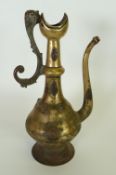 AN ISLAMIC BRASS EWER OR COFFEE POT, baluster form, with crescent shaped rim and raised on a